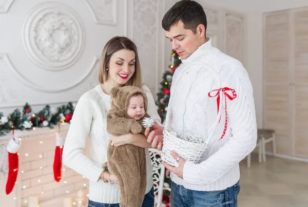 Lindo niño en traje de oso y sus maravillosos padres de pie juntos cerca de las decoraciones de Navidad — Foto de Stock