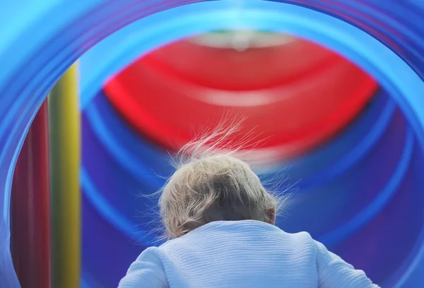 Маленька допитлива дівчинка виглядає в синьому повзунку в парку розваг — стокове фото