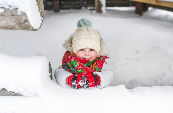 Happy baby girl in red russian scarf on snow background. Closeup portrait — Stock Photo, Image