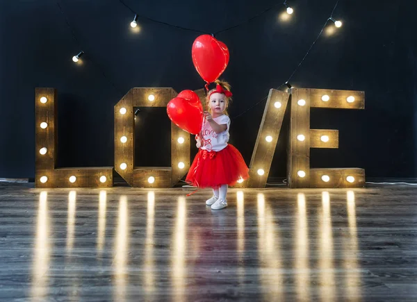 Dulce niñita con corazón rojo. Niña feliz con globo rojo . — Foto de Stock