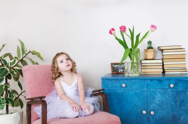  Ev Oda sandalyede oturan sevimli küçük kız.