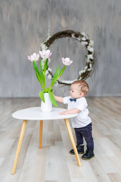 A small child with a bouquet of white tulips. A boy with a gift of flowers in a vase — Stock Photo, Image