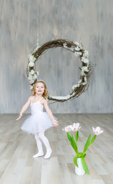 Pequena linda bailarina em vestido branco e tulipas está posando em um belo estúdio . — Fotografia de Stock