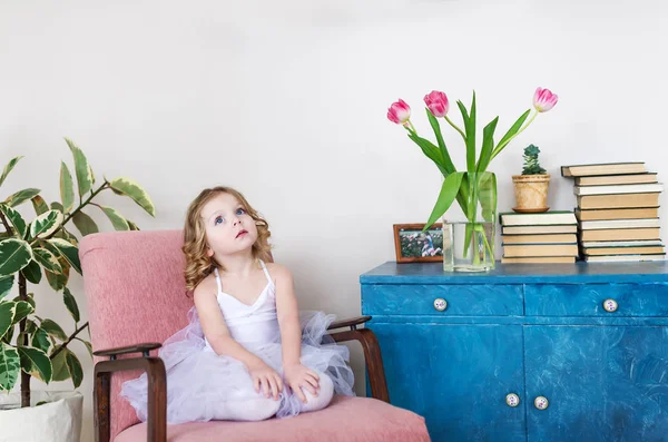 Linda niña sentada en silla en la habitación de casa . — Foto de Stock