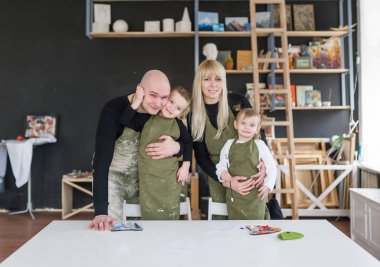 Çocuklarda yeşil önlük ile genç mutlu çift ayakta. 