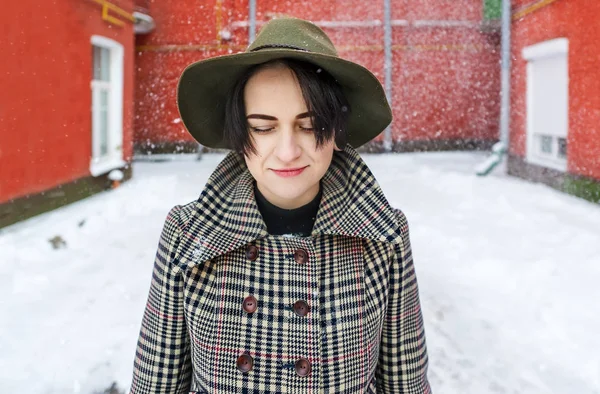 Mujer joven en un sombrero en un patio rojo de la ciudad de invierno — Foto de Stock