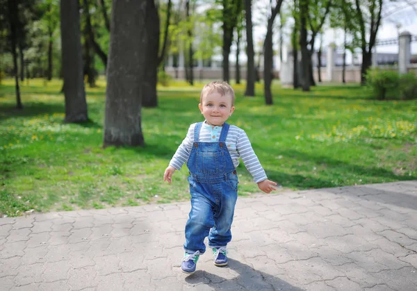 Schattige babyjongen met zoete glimlach, staat in een grappige pose in de groene stad park natuur. — Stockfoto