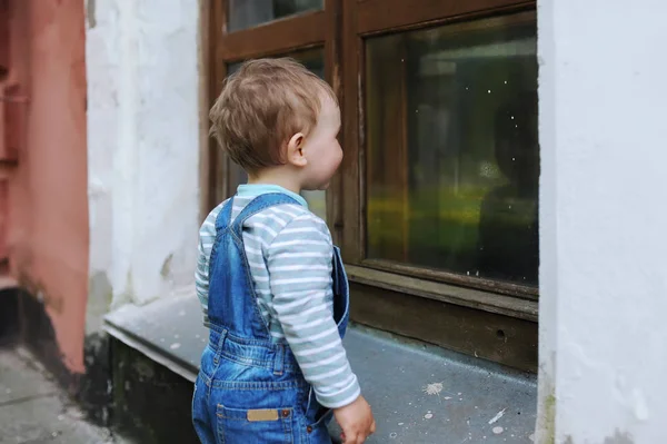 El niño mira el reflejo en una ventana del edificio de la ciudad — Foto de Stock