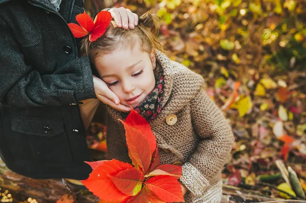 Hermano pequeño con cara cariñosa de hermanita. Niña con hojas rojas de otoño . — Foto de Stock