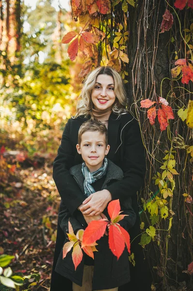 Portrait d'une jeune mère heureuse et de son fils. Ils posent dans le parc d'automne . — Photo