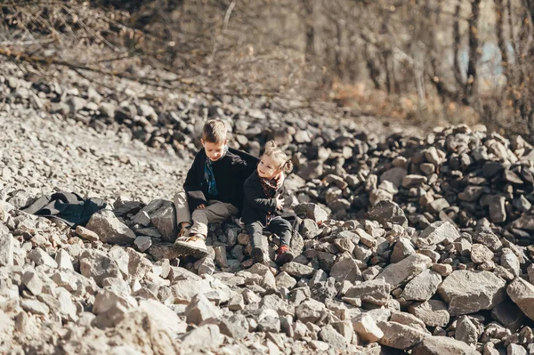 Dzieci siedzące na kamieniach na brzegu jeziora. — Zdjęcie stockowe