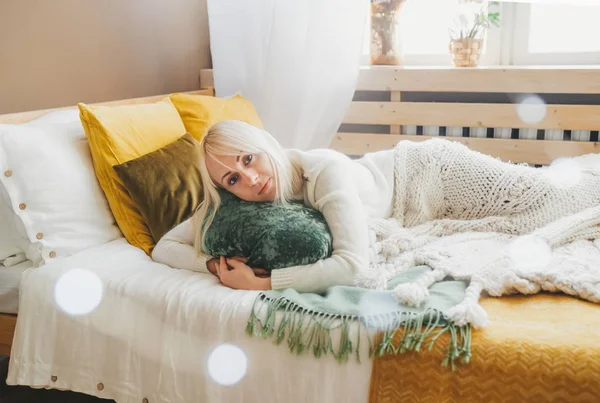 Щаслива блондинка лежить на ліжку біля вікна . — стокове фото