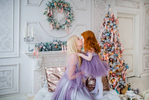 Молодая мать и ее маленькая дочь целуются в уютной белой гостиной в канун Рождества . — стоковое фото
