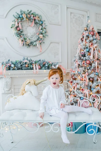 Niña de heredero rojo con la boca abierta posa en una habitación decorada con Navidad — Foto de Stock