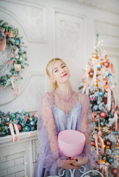 Блондинка в фиолетовом платье держит в руках новогодний подарок . — стоковое фото
