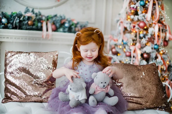 Roodharig kind met twee kleine teddyberen spelen in de woonkamer versierd met kerstaccessoires. Rechtenvrije Stockfoto's