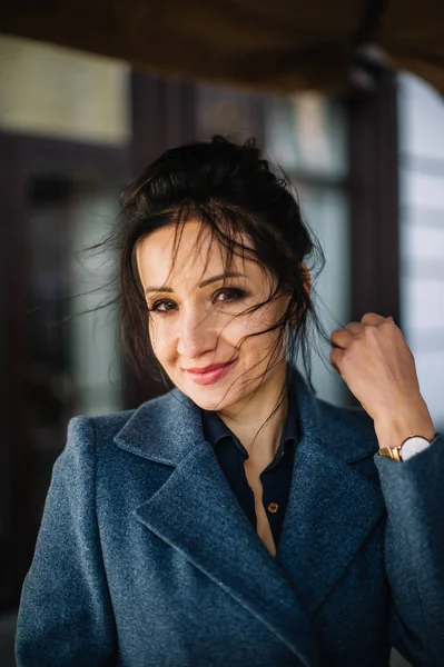 Élégant portrait de femme brune avec des cheveux bouclés dans un manteau bleu — Photo