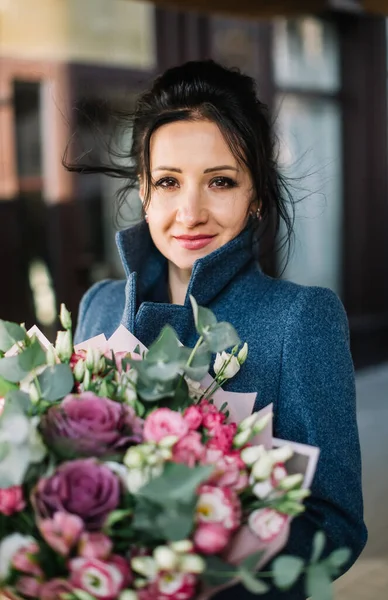 Gros portrait de belle femme brune tenant un bouquet de roses — Photo