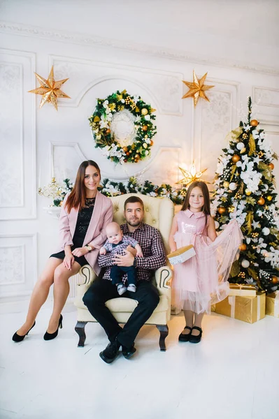 Feliz padre se sienta en un sillón y su gran familia está junto a un árbol de Navidad — Foto de Stock