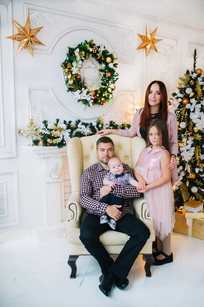 Imagen del padre con su familia sentada en un sillón junto al árbol de Año Nuevo en la sala de estar festiva — Foto de Stock