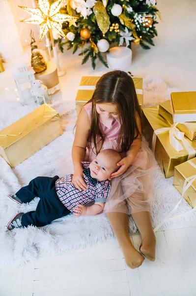 El hermanito y la hermanita juegan en casa, desempaquetan regalos. Ambiente de vacaciones. Vista superior — Foto de Stock