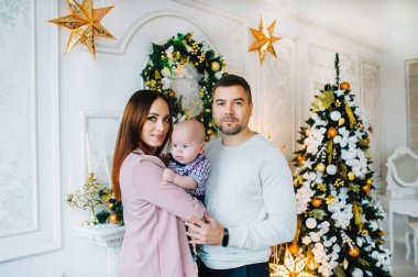 Anne ve baba, Noel ağacının önünde küçük bir çocukla dikiliyorlar..