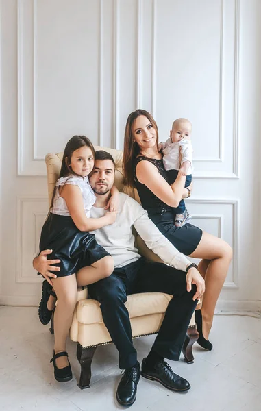 Retrato de padres con dos hijos en sillón en el interior . — Foto de Stock