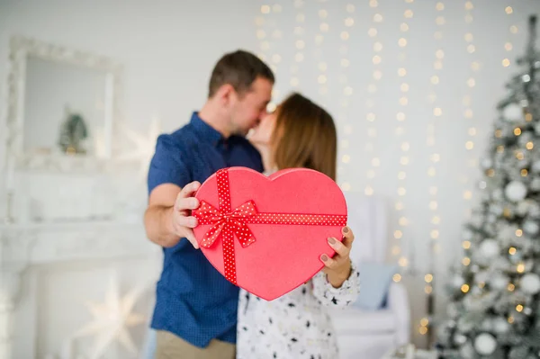 Feliz joven pareja enamorada, con corazón rojo caja de dulces en las manos en primer plano . — Foto de Stock