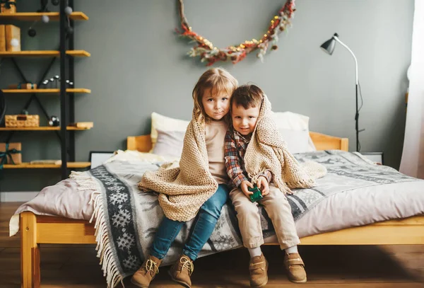 Retrato de dos niños hermanos felices sentados en la cama bajo cuadros — Foto de Stock