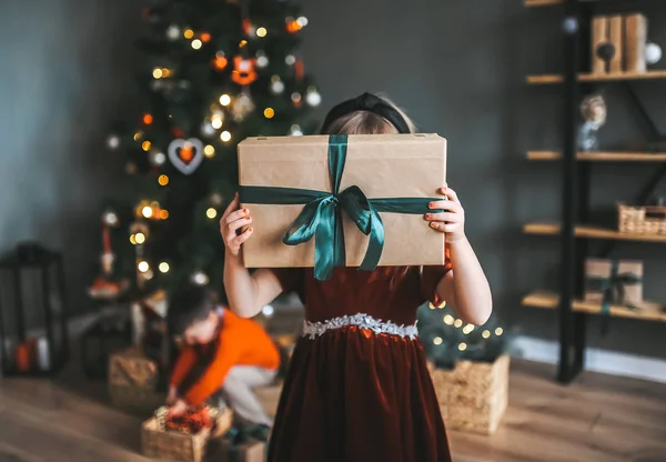 Niña escondida detrás de una gran caja de regalo. Alegre linda niña con presente . —  Fotos de Stock