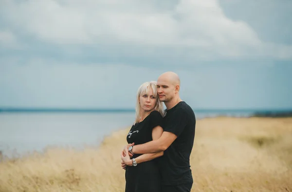 Vista romântica de casal em roupas pretas quando se abraçam na borda da costa rochosa do mar Báltico . — Fotografia de Stock