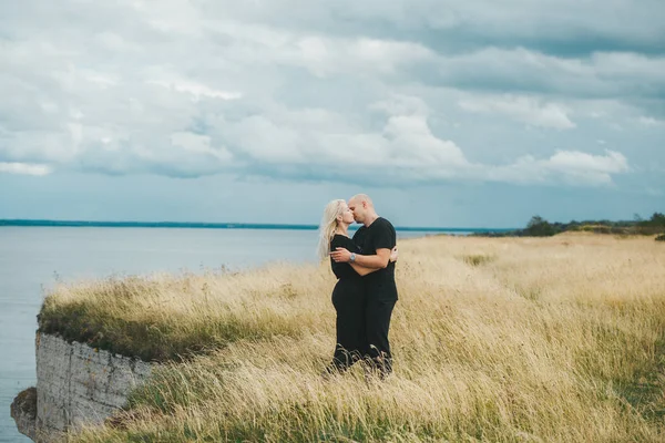 Vista romantica di coppia in abiti neri quando si baciano sul bordo della costa rocciosa del Mar Baltico . — Foto Stock