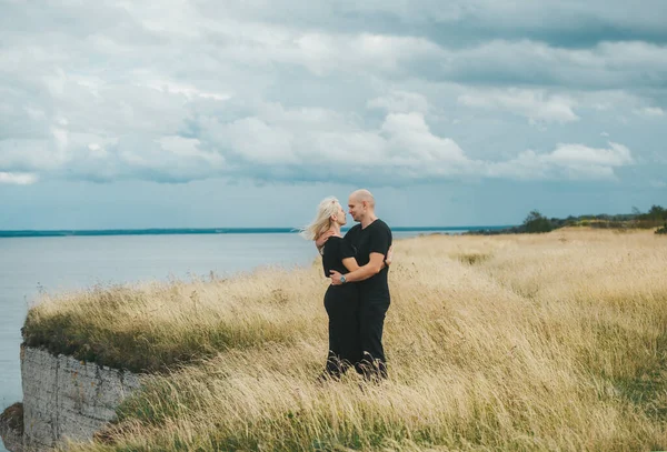 Ρομαντική θέα ζευγαριού με μαύρα ρούχα όταν αγκαλιάζονται στην άκρη της βραχώδους ακτής της Βαλτικής θάλασσας. — Φωτογραφία Αρχείου
