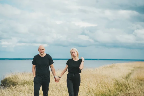 Couple en noir marchant sur le bord de la côte de la mer Baltique . — Photo
