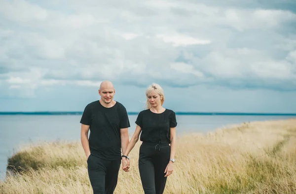 Romantyczny widok na parę w czarnych ubraniach, gdy chodzą na skraju skalistego wybrzeża Morza Bałtyckiego. — Zdjęcie stockowe