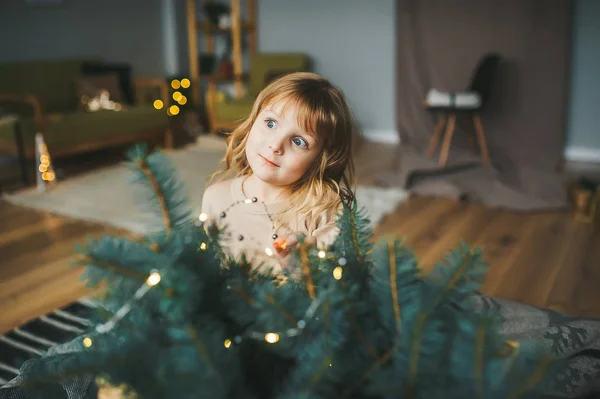 Una niña asombro contra el fondo de la rama del árbol de Navidad . — Foto de Stock
