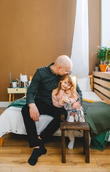 Отец целует девочку на лбу дома в спальне — стоковое фото