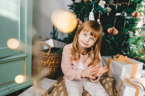 Niña sentada en el suelo con regalos bajo el árbol de Navidad. Retrato de primer plano — Foto de Stock