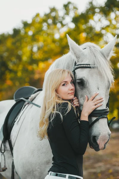 Beautiful blonde woman with long hair next horse — ストック写真