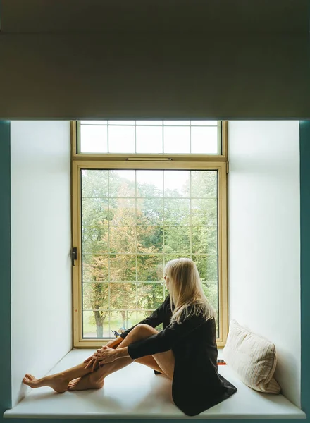 Piękna blond dziewczyna, siedząc na parapecie — Zdjęcie stockowe