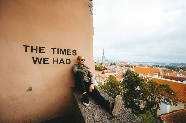 Um jovem turista careca em óculos de sol inspeciona uma cidade a partir da altitude de voo do pássaro . — Fotografia de Stock