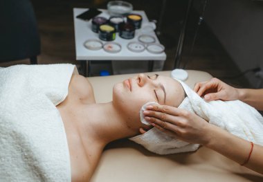 Kozmetik uzmanı kozmetoloji odasında bir kızın yüzünü soyduğu için sünger maskesini çıkardı.