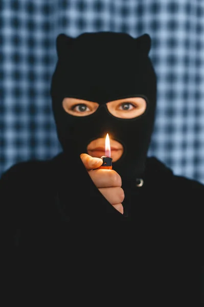 Mulher de véu preto com isqueiro na frente em um fundo azul. Conceito para religião islâmica e terrorismo . — Fotografia de Stock