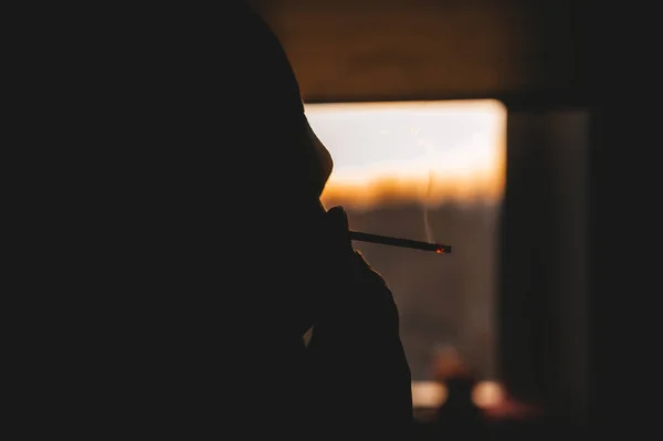 A mysterious woman smokes a cigarette. Side view. — Stock Photo, Image