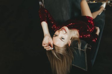 Koltuğunda oturan kırmızı elbiseli, gülümseyen güzel sarışın kadın. Üst görünüm