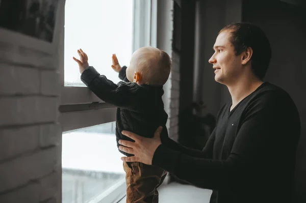 白人の父親と彼女の子供は窓辺に立ってガラスを見ている。ライフスタイル. — ストック写真