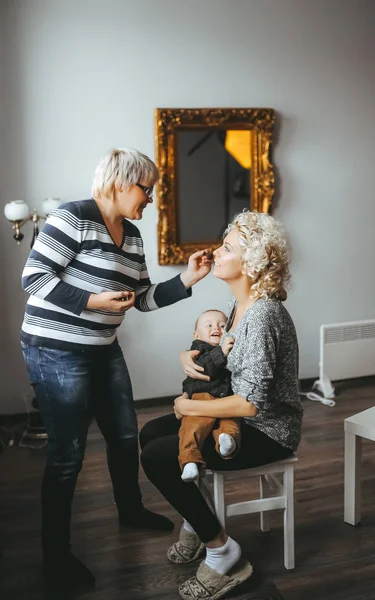 Professional makeup artist applying make-up for young blonde mother — Stock Photo, Image