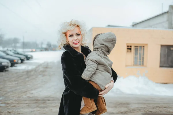 Portrait de jeune mère blonde tenant son petit fils dans la rue en hiver — Photo