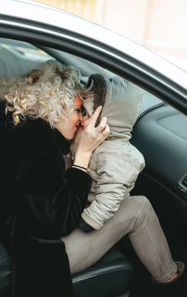 Mother kissing her little son and they goes to winter travel trip in the car — 스톡 사진