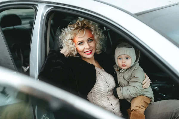Una bella donna bionda con il trucco con il suo bambino seduto in macchina — Foto Stock